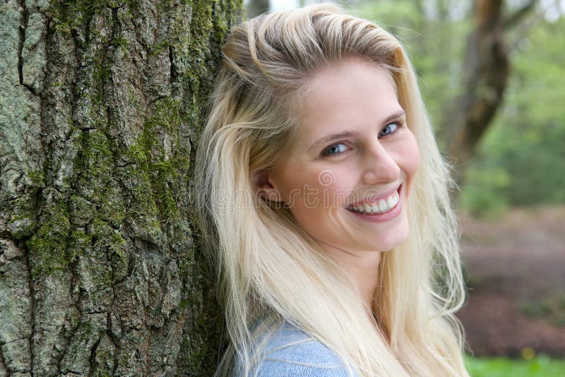 Beautiful blond woman smiling in the forest