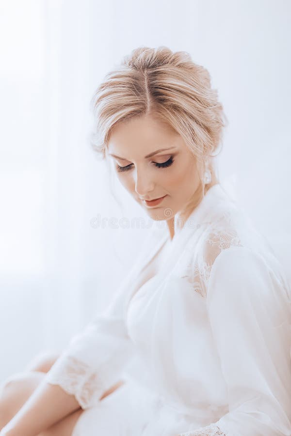 Beautiful blonde bride with stylish make-up in white dress.Morning bride