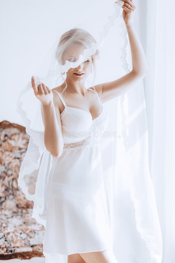 Beautiful blonde bride with stylish make-up in white dress.Morning bride