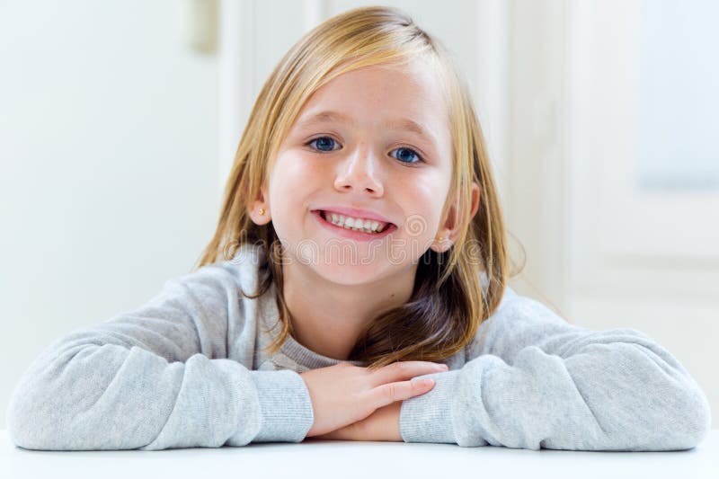 Beautiful Blonde Child Sitting at a Table in Kitchen. Stock Image