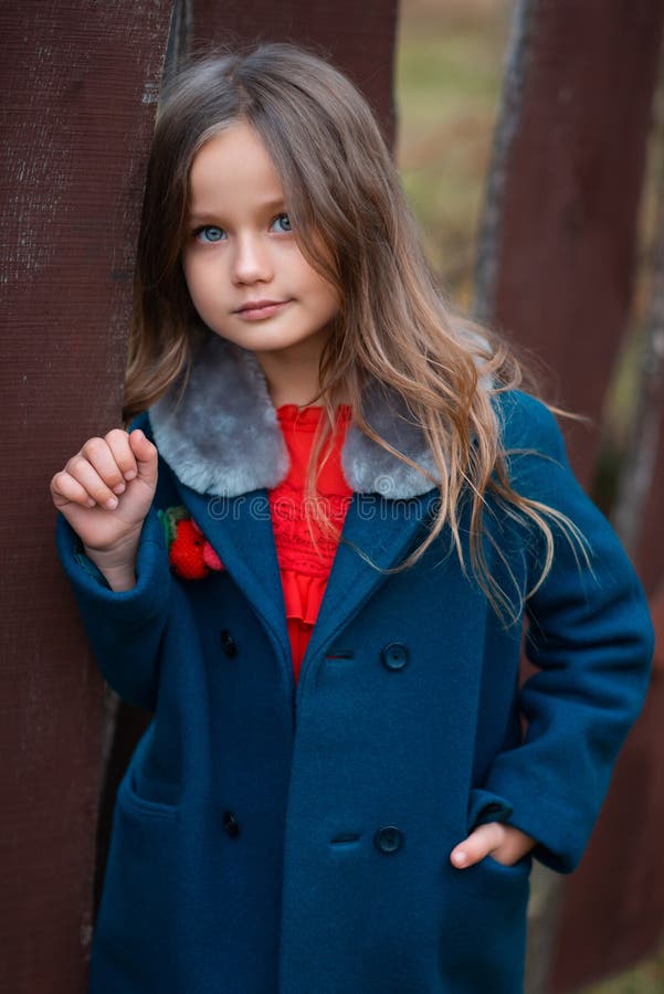 A Beautiful Blonde Girl with Blue Eyes and a Coat Standing Near the ...