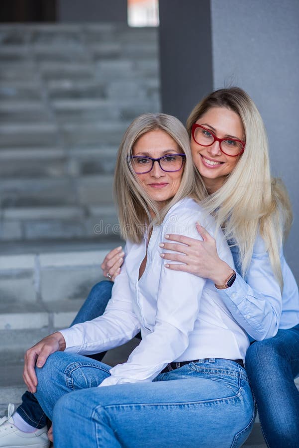 A Beautiful Blonde With Glasses And Her Mature Mother Are Sitting On 