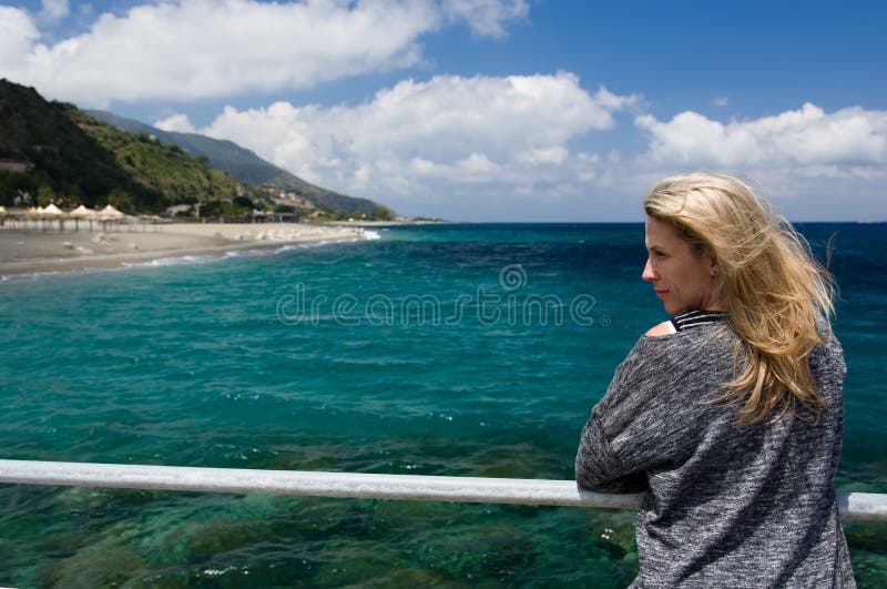 Blonde woman outdoor, azure blue sea background, beach and mountan