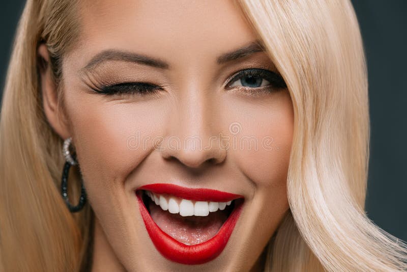 Beautiful blonde winking woman, isolated on grey. Charming elegant european woman stock images, royalty-free photos and pictures