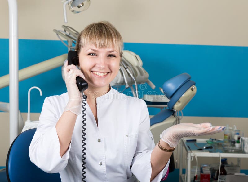 Beautiful blonde woman administrator at the dental clinic holding the phone, records of patients at the reception stock photo Beautiful blonde woman administrator at the dental clinic holding the phone, records of patients at the reception stock photo