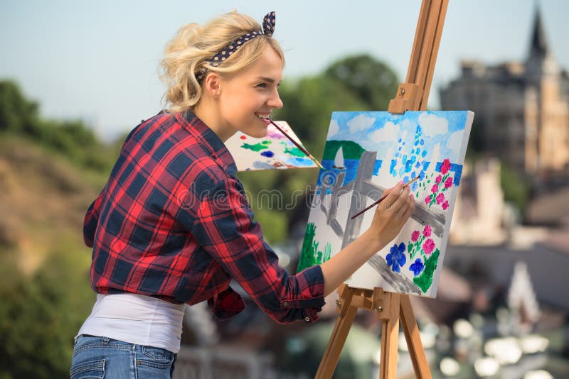 Beautiful blonde woman artist paints a colorful