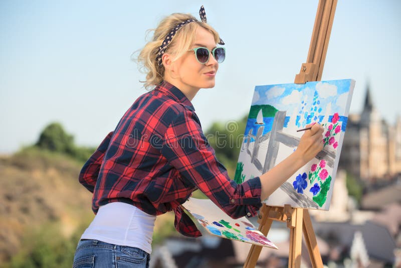 Beautiful blonde woman artist paints a colorful