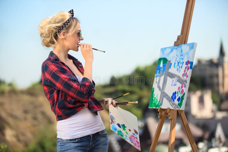 Beautiful blonde woman artist paints a colorful