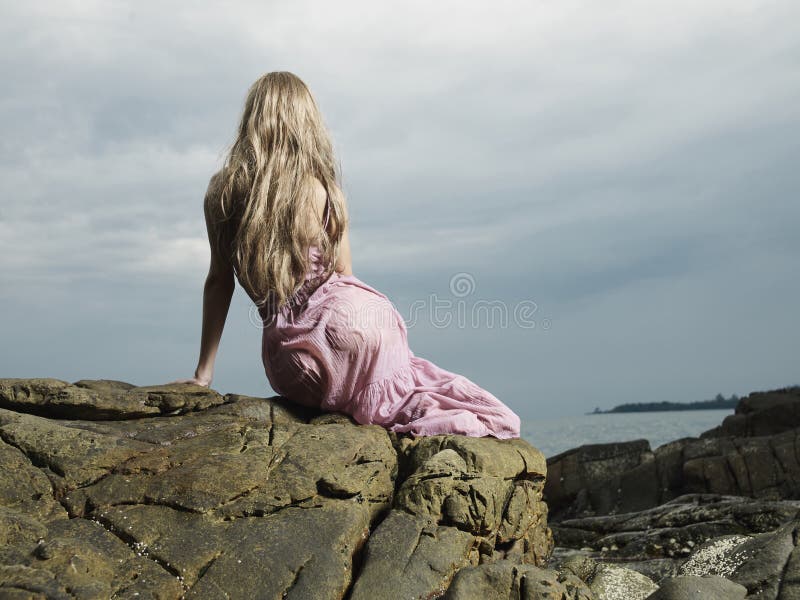 Beautiful blonde woman on the beach. Lady in pink dress