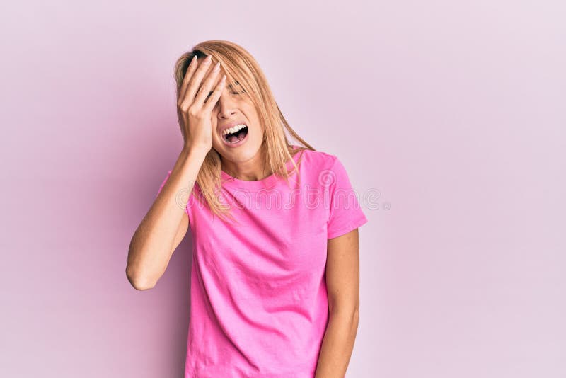 Beautiful blonde woman wearing casual pink tshirt yawning tired covering half face, eye and mouth with hand