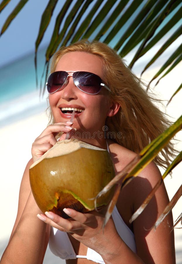 Beautiful blondy holding coconut in tropical beach