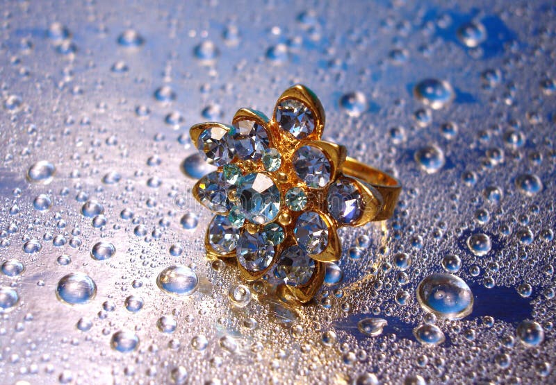 Beautiful blue ring on silver background with drop of water