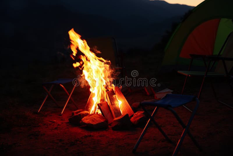Bonfire and Folding Chairs Near Camping Tent Outdoors at Night Stock