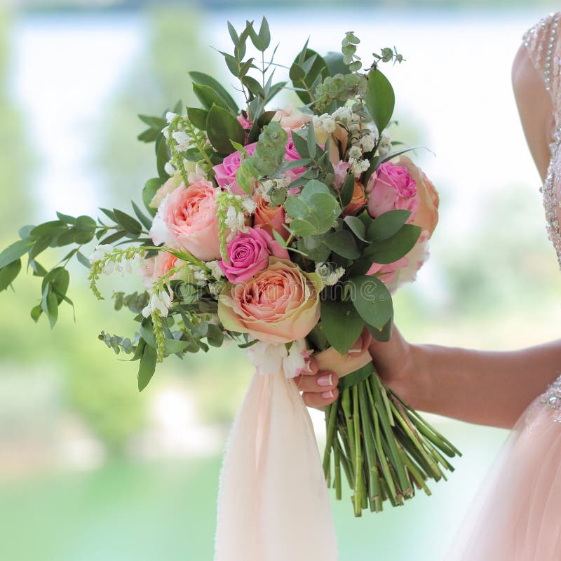Beautiful bridal bouquet in hands of the bride. Wedding bouquet of peach roses by David Austin, single-head pink rose aqua