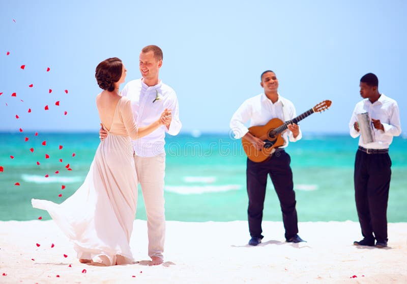 Beautiful bride and groom dancing on tropical beach, live music