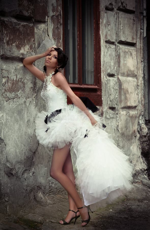 Beautiful bride leaning against the wall of an old building