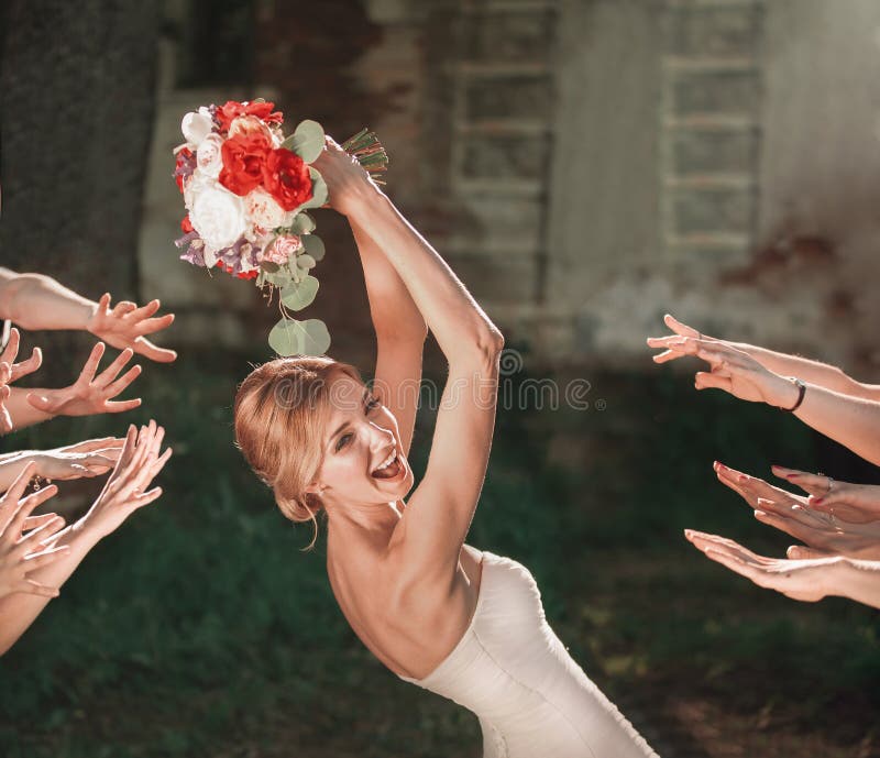Beautiful bride throws wedding bouquet to her friends
