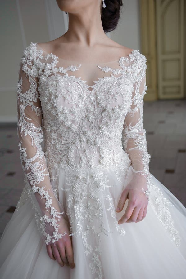 Beautiful bride in a wedding dress in a luxurious white room with a large chandelier