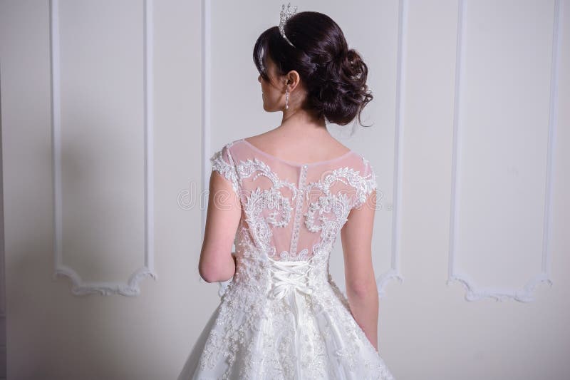 Beautiful bride in a wedding dress in a luxurious white room with a large chandelier