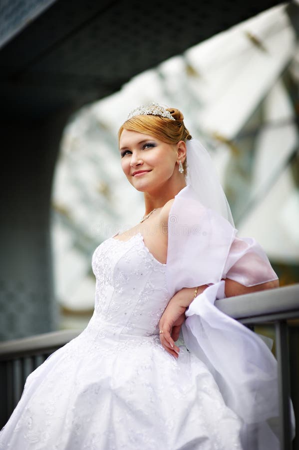 Beautiful bride in a wedding dress near parapet