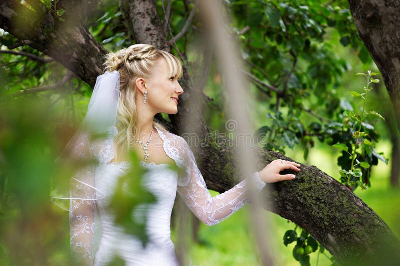 Beautiful bride in wedding dress in park