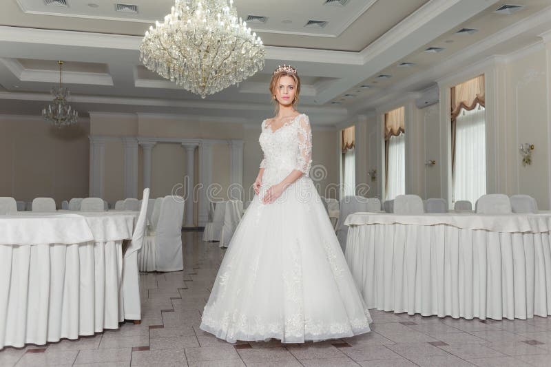 Beautiful bride in a wedding dress in white interior