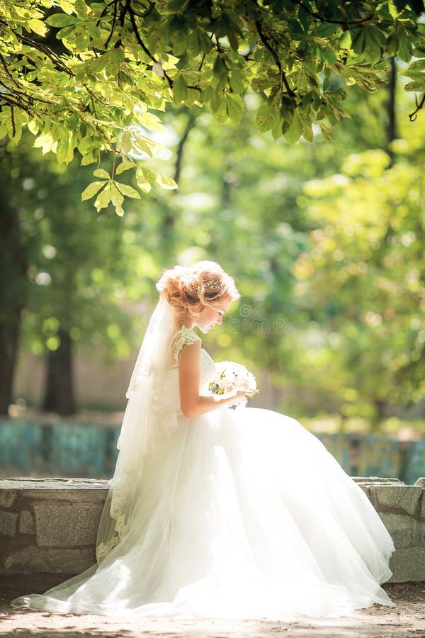 Beautiful bride in white dress in the autumn garden