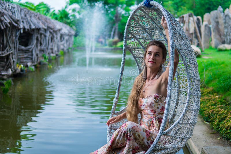 Beautiful brunette in dress swinging on a swing over the water in the Park in Sunny day royalty free stock photography Beautiful brunette in dress swinging on a swing over the water in the Park in Sunny day royalty free stock photography
