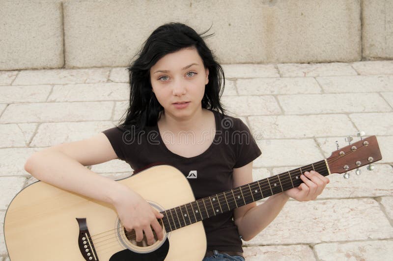 Beautiful Brunette Girl Playing a Guitar