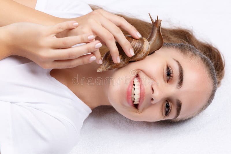 Beautiful girl with a snail on her face on a white background