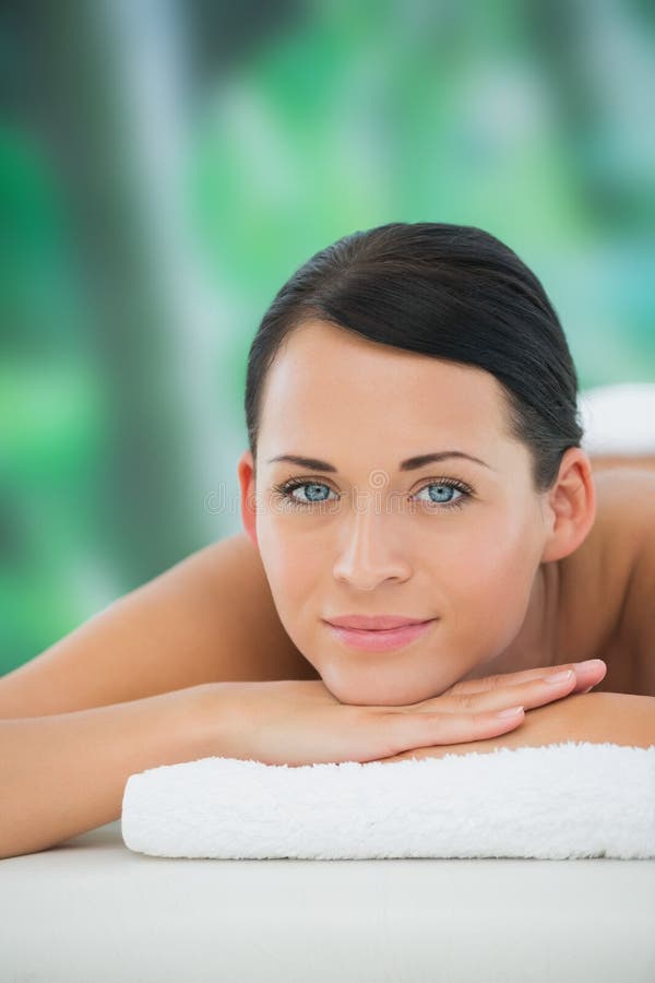 Beautiful Brunette Relaxing On Massage Table Smiling At Camera Stock