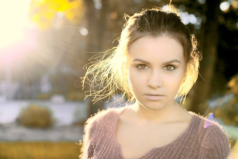 A beautiful brunette stands in autumn sun light