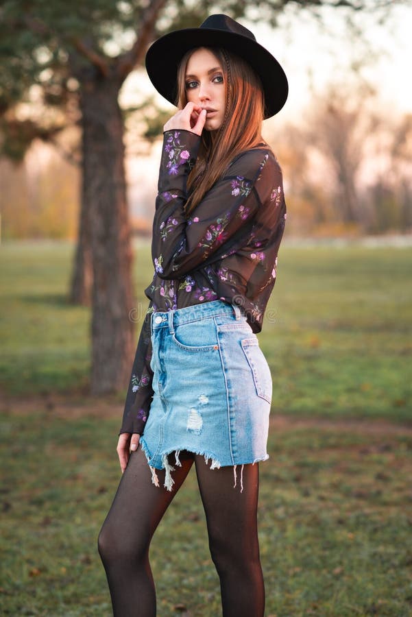 Beautiful girl in denim shorts and tights in a grid. Rock style.  Fashionable girl. Dark background. Beautiful, young brunette. Casual wear.  Trend clothing. Stock Photo