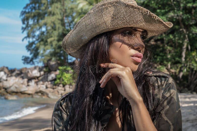 Beautiful brunette woman with straw hat and sunglasses in tropical forest