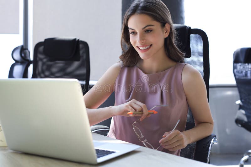 Beautiful business woman in smart casual wear working on laptop in the office