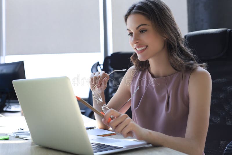 Beautiful business woman in smart casual wear working on laptop in the office