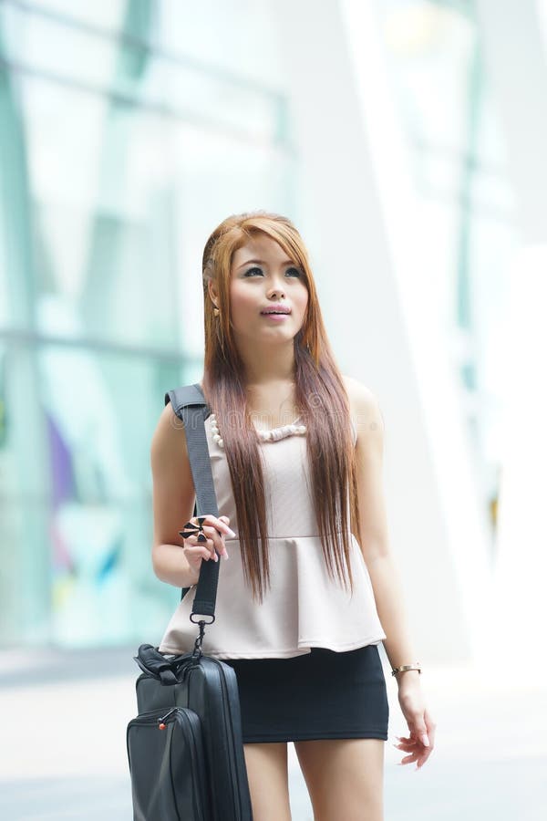 Beautiful business woman walking outside her office with briefcase.