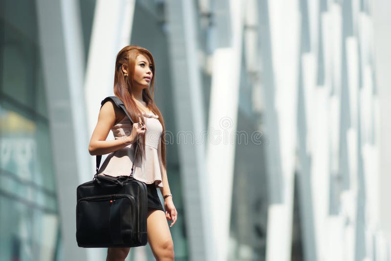 Beautiful business woman walking outside her office with briefcase