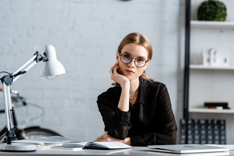 Beautiful businesswoman in black clothes and glasses sitting on chair and royalty free stock photography Beautiful businesswoman in black clothes and glasses sitting on chair and royalty free stock photography