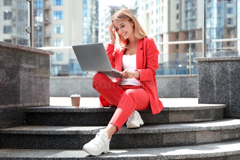 Beautiful businesswoman with laptop sitting on stairs