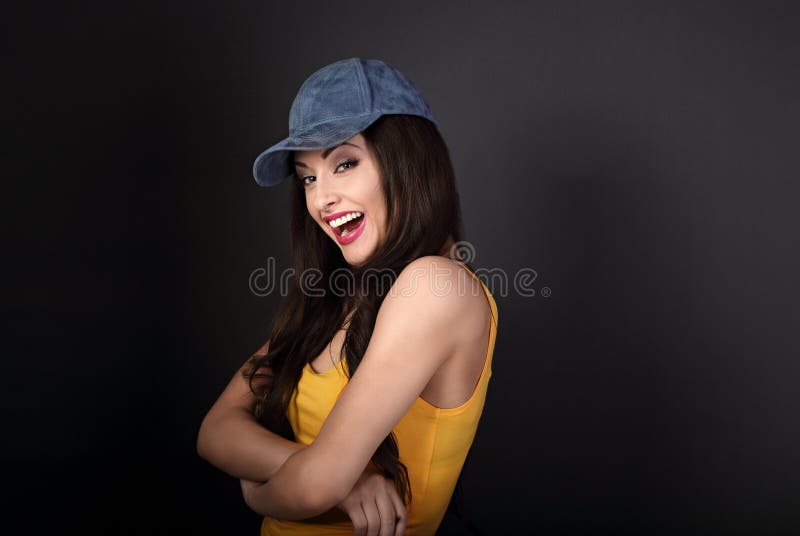 Beautiful casual joyful woman in blue baseball cap and yellow to