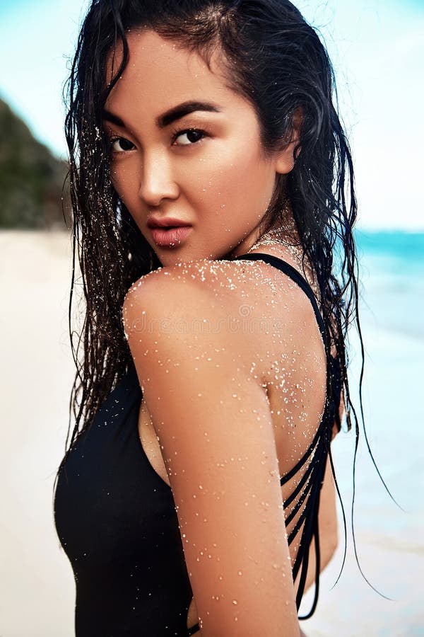 Portrait of beautiful caucasian sunbathed woman model with dark long in  swimsuit posing on summer beach