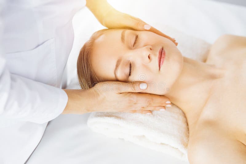 Beautiful Caucasian Woman Enjoying Facial Massage With Closed Eyes In Sunny Spa Salon Relaxing