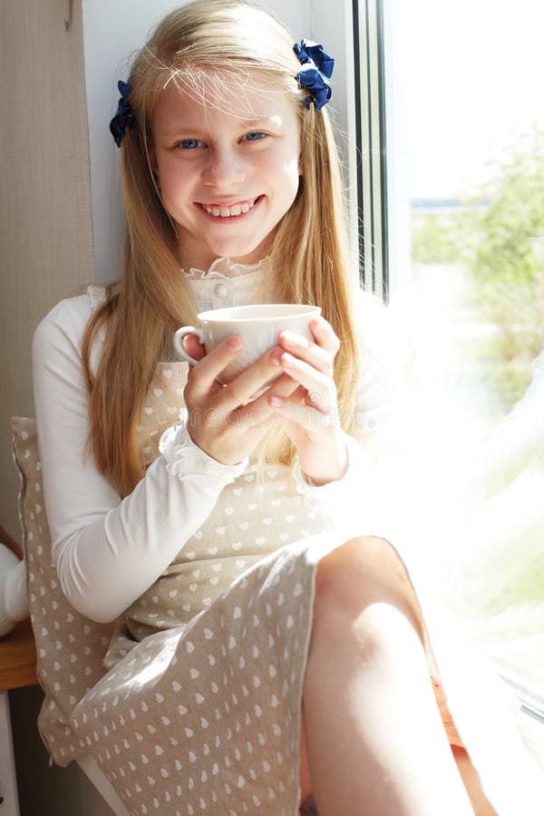 Beautiful child drinking tea and looking through window