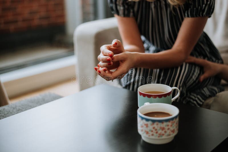 Beautiful closeup shot of two cups of tea on a black table and a female wearing a dress stock photography Beautiful closeup shot of two cups of tea on a black table and a female wearing a dress stock photography