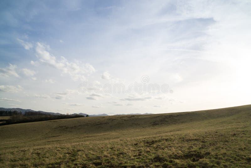 Beautiful clouds over the green meadow, paths and trees, during sunrise or sunset.