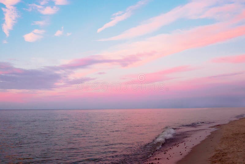Beautiful cloudy sunset and seascape. Pink and blue sky reflected in the dark water in the evening