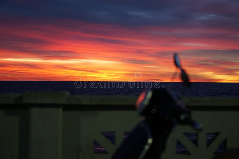 Sunrise with scooter on the forefront. Beautiful colored clouds at sunrise over wide river with scooter on the forefront stock photography Sunrise with scooter on the forefront. Beautiful colored clouds at sunrise over wide river with scooter on the forefront stock photography