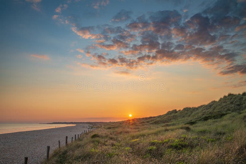 Beautiful vibrant Summer sunset beach landscape with stunning sk