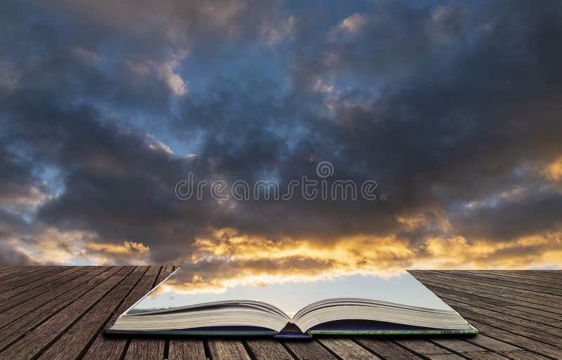 Beautiful colorful vibrant golden hour sunset skyscape with cloud formation and setting sun in pages of open book, story telling